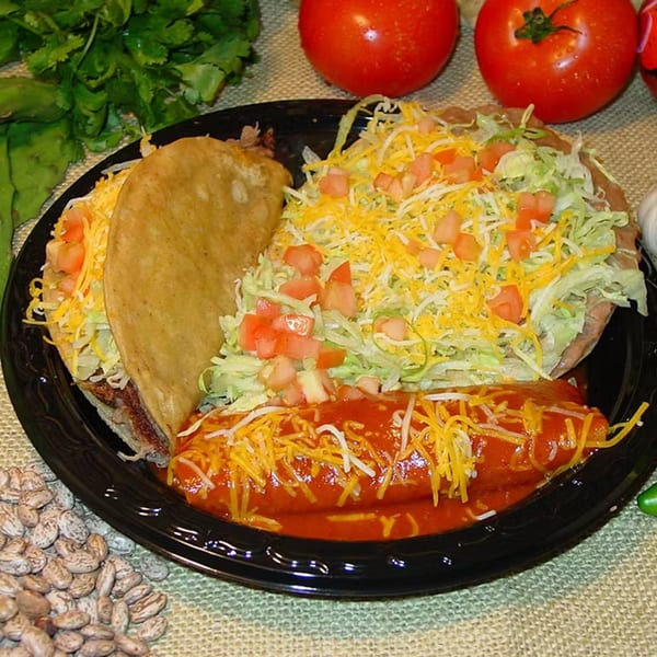 A Los Portales Taco Shop combo plate with a taco, tostada, and enchilada, garnished with cheese and lettuce.