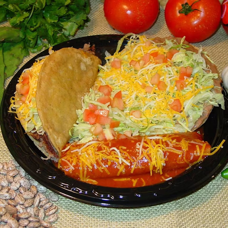 A Los Portales Taco Shop combo plate with a taco, tostada, and enchilada, garnished with cheese and lettuce.