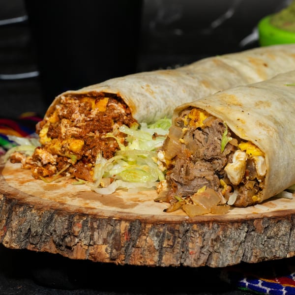Two large, cut Los Portales burritos, one with chorizo and one with steak, on a wooden board.
