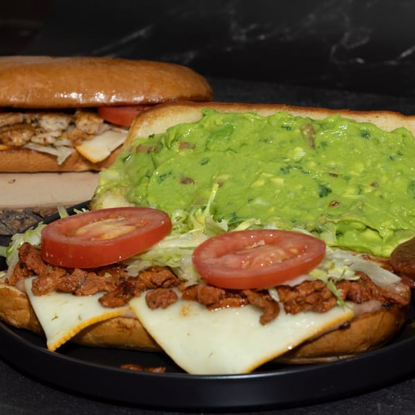 Two Los Portales Taco Shop tortas, one with guacamole, tomatoes, and meat, the other with chicken.