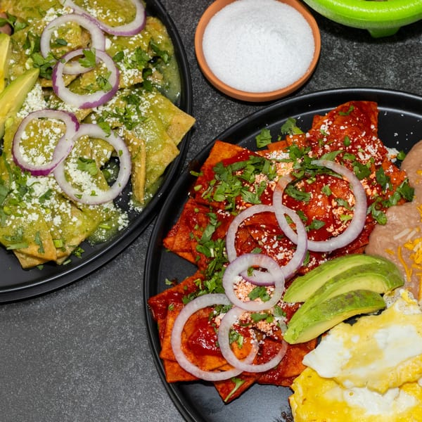 Two plates of Los Portales Taco Shop chilaquiles, one green and one red, with sides.